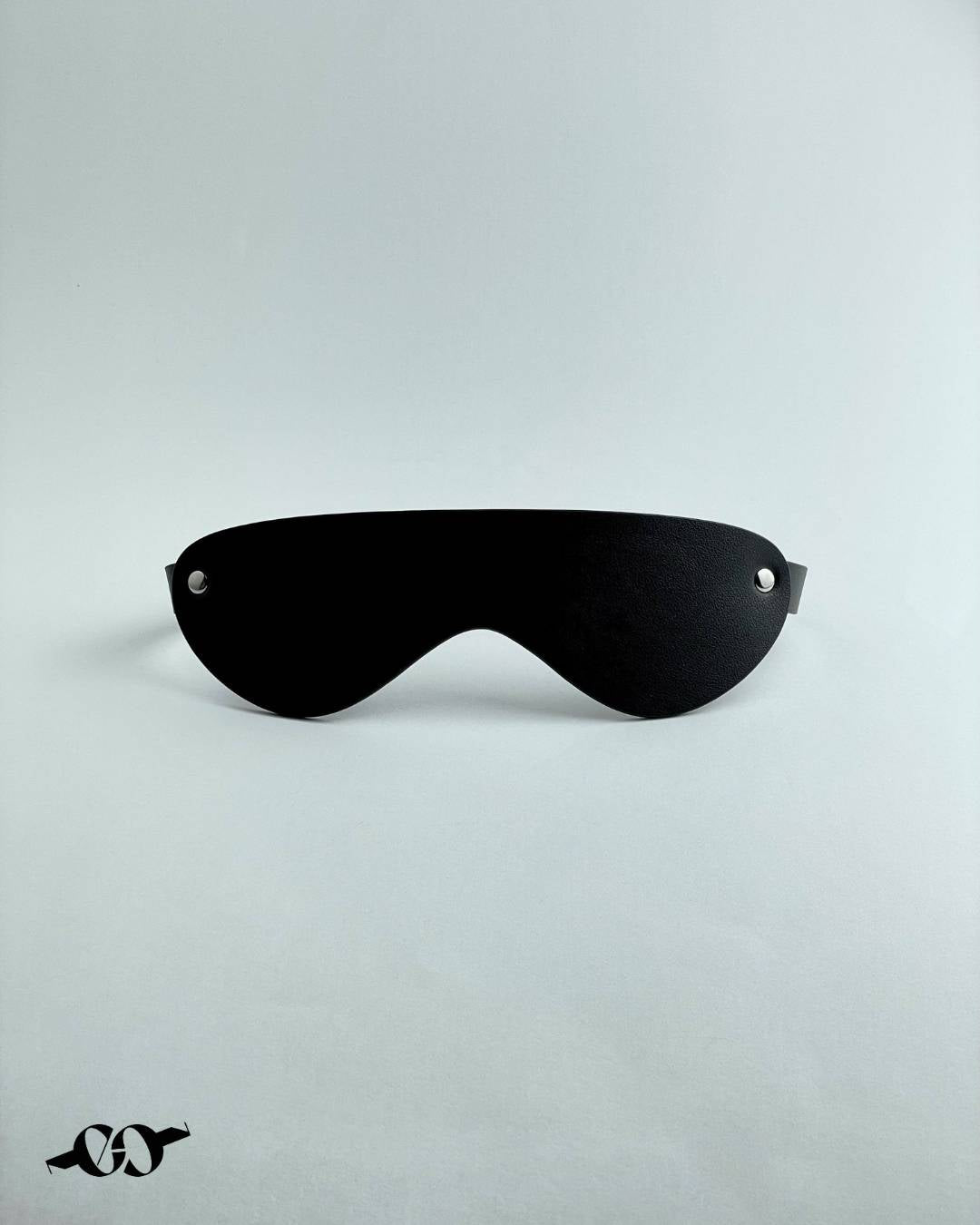 A black leather BDSM blindfold with buckle closure, displayed against a white background.