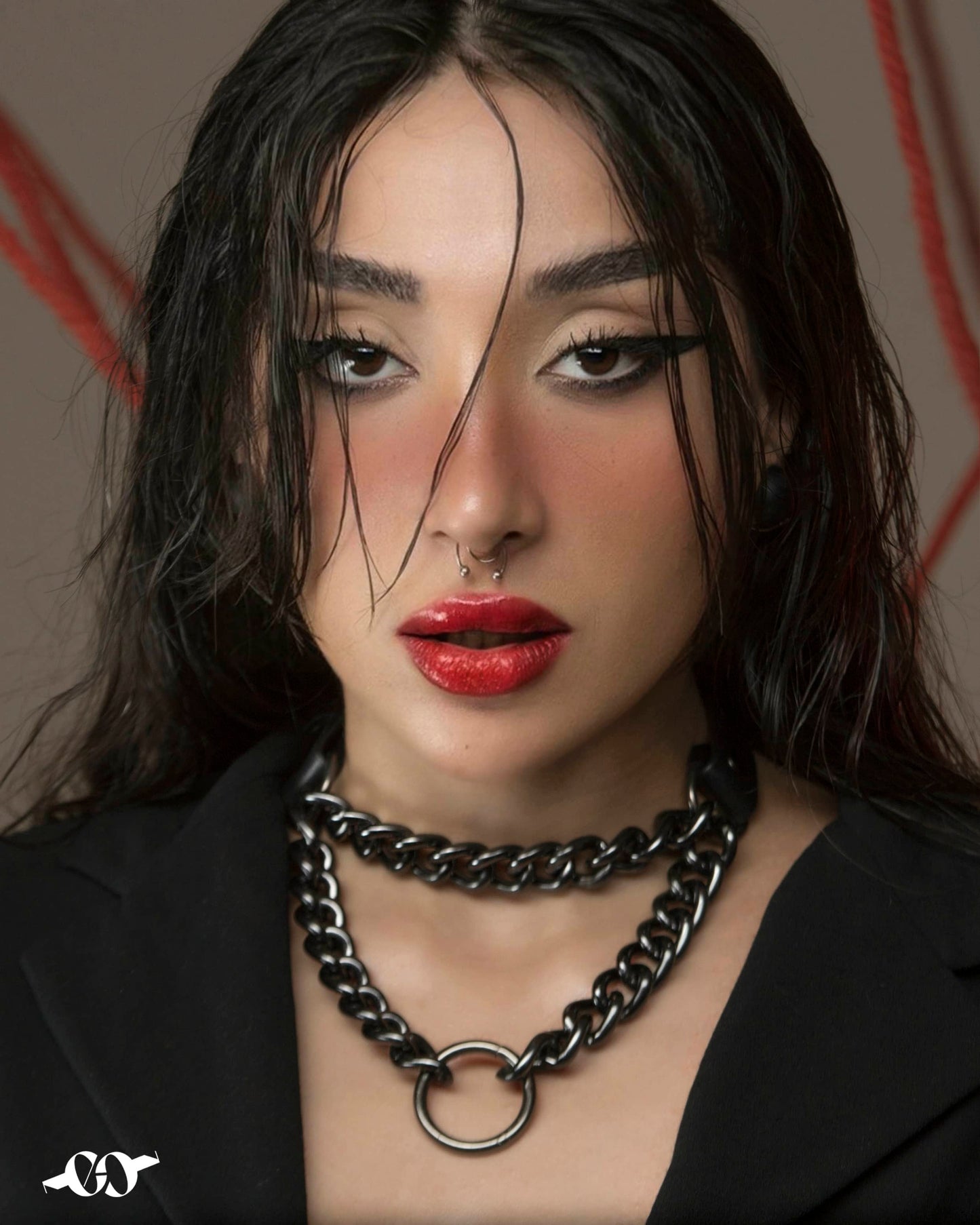A person wearing a leather choker necklace with a black and silver color scheme, displaying a bold and confident expression.