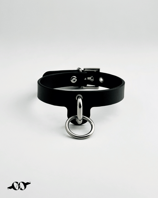 A black leather O ring collar with a metal O ring attachment, displayed against a white background.