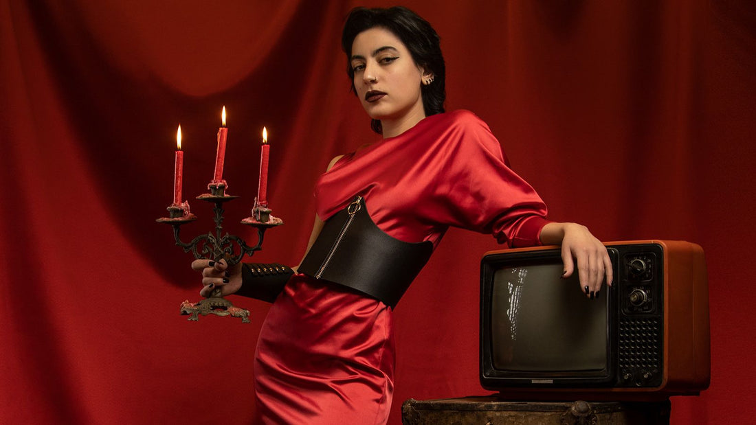 Model in a red satin dress wearing a black leather underbust corset belt
