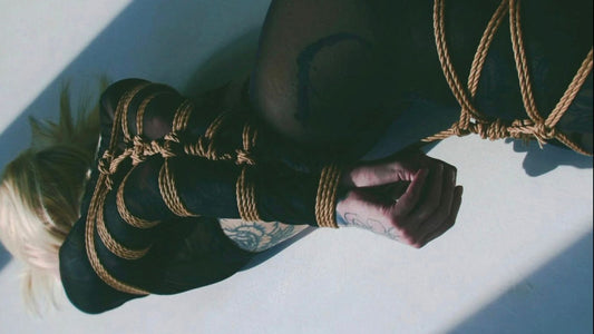 Natural jute shibari rope wrapped around the legs and arm of a reclining figure