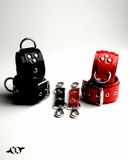 The image features two red leather cuff bracelets and two black leather cuff bracelets, displayed against a neutral background. Each cuff has a buckle closure and metal rings for adjustability.